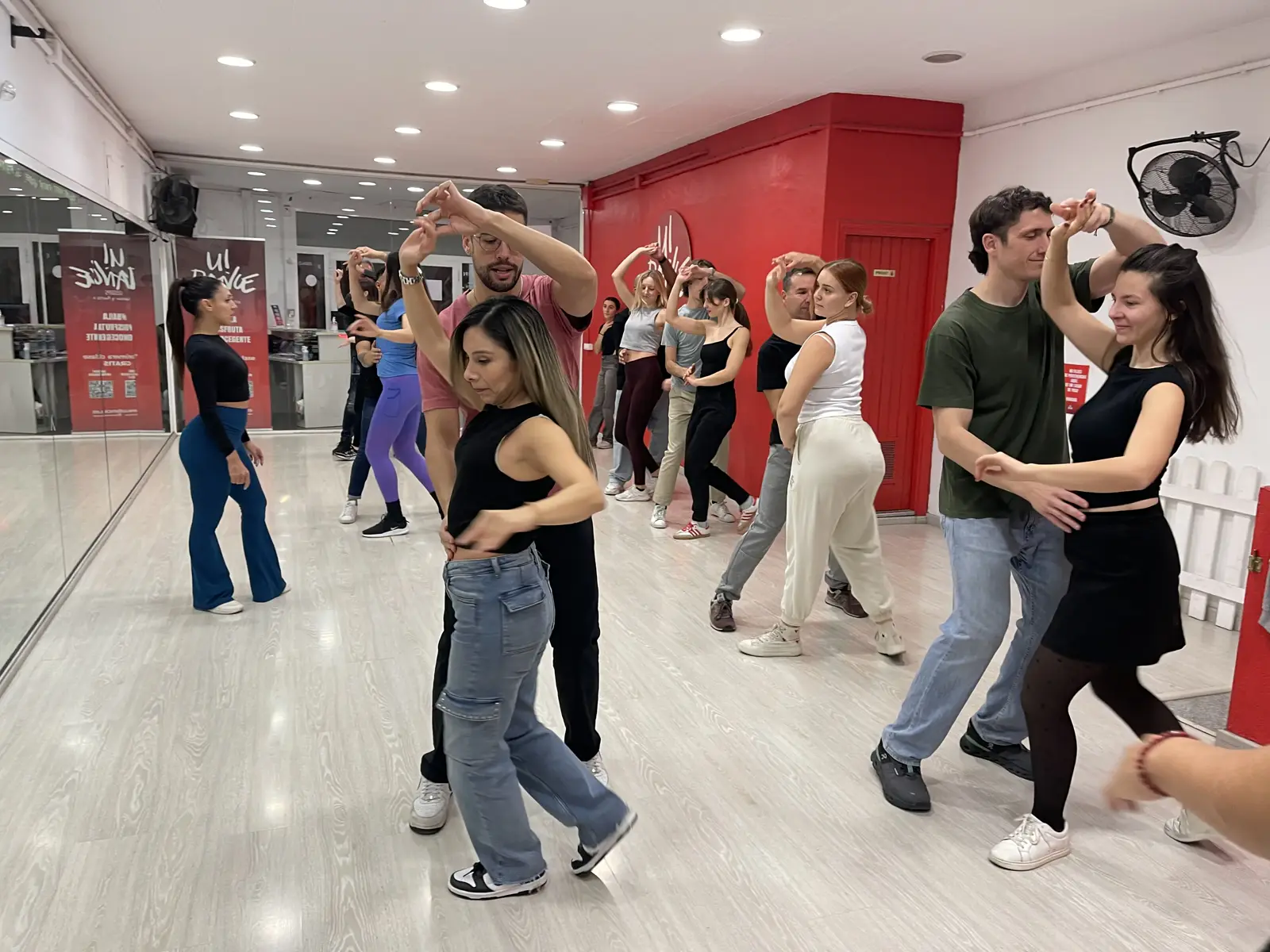 Grupo de alumnos bailando salsa en pareja en la sala de U!DANCE Lesseps, en Gràcia